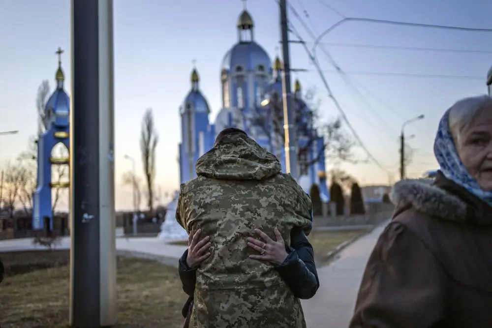 Солдат обіймає родича, який тікає від війни, за кілька хвилин до відправлення автобусом до Польщі, у Вінниці, Україна, середа, 16 березня 2022 року. (Фото: Rodrigo Abd/AP.)