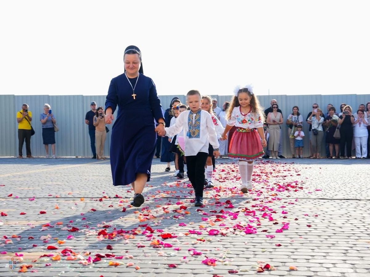 Діти крокують за парти з першою вчителькою.