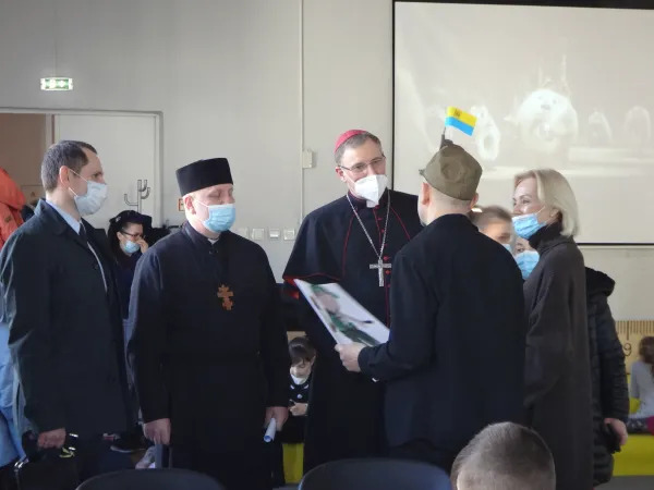 Леонід Гребенник, отець Роман Сапужак, архиєпископ Станкевич і Габріелла Каб’єр під час візиту спілкуються з українським біженцем